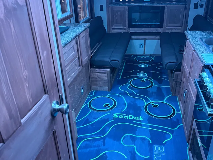 Custom blue SeaDek ice-house floor with teal topographic contour lines, ice-fishing holes, and the SeaDek and BlueWater logos routed in